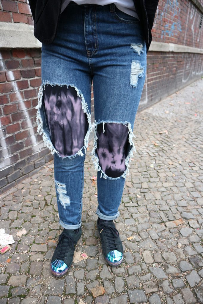 Zerrissene Jeans mit einer Kompressionsstrumpfhose in Batik